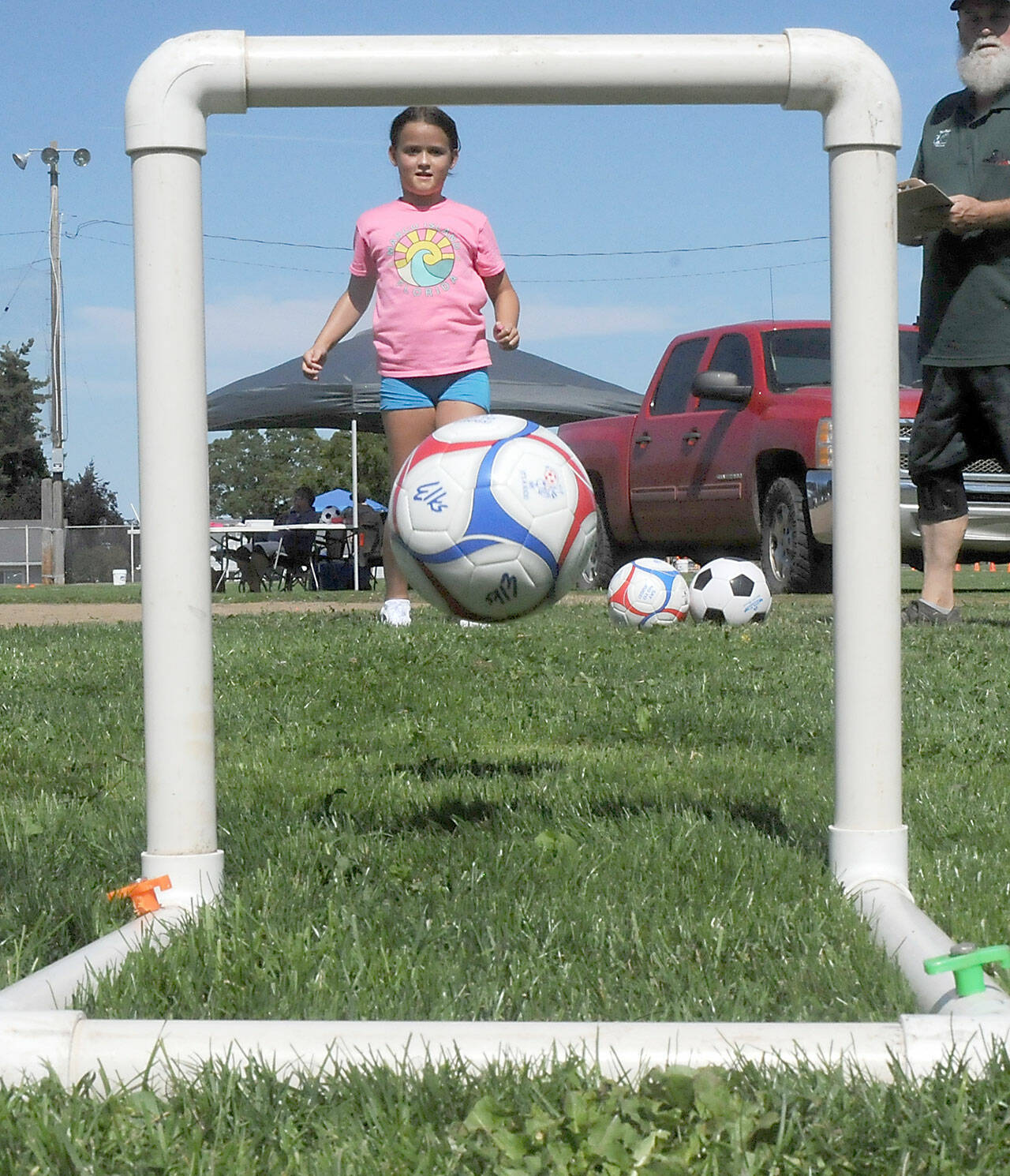 Kyra Toner, 8, of Burien kicks a soccer ball through a narrow goal as part of an informal soccer skills test during Saturday’s Party at the Park at Elks Playfield in Port Angeles. The event, hosted by the Port Angeles Naval Elks Lodge, featured a variety of activities for children and adults, food and live music. (Keith Thorpe/Peninsula Daily News)