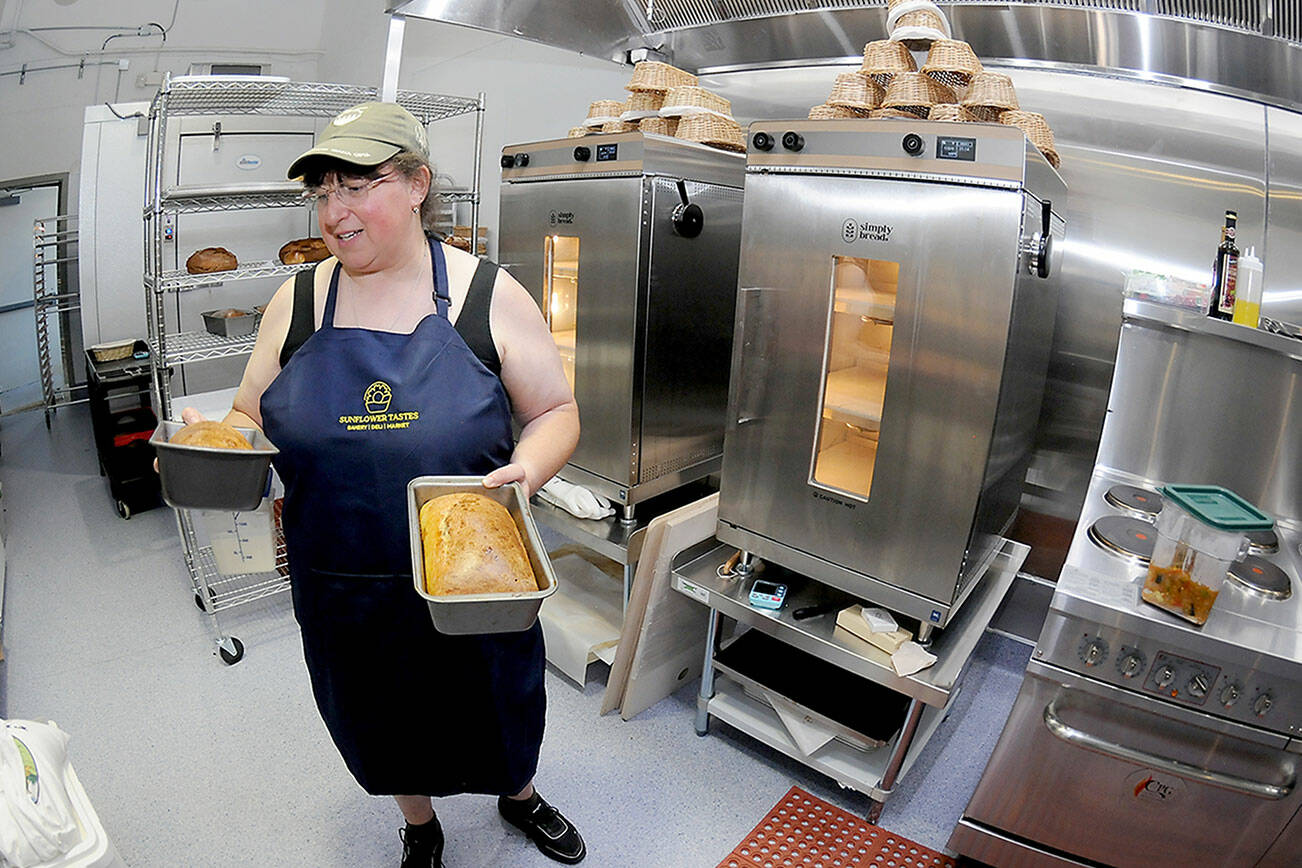 Kate Orzikh, owner of Sunflower Tastes bakery and deli at The Wharf in Port Angeles, holds loaves of sourdough bread created in the establishment’s kitchen. (Keith Thorpe/Peninsula Daily News)