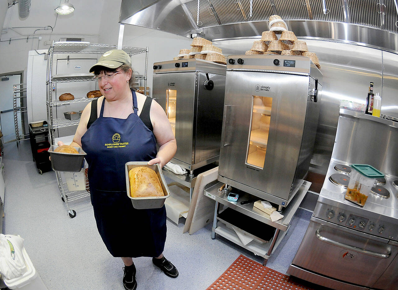 Kate Orzikh, owner of Sunflower Tastes bakery and deli at The Wharf in Port Angeles, holds loaves of sourdough bread created in the establishment’s kitchen. (Keith Thorpe/Peninsula Daily News)
