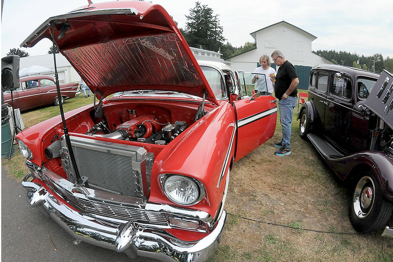 Vintage car owner Alfred Dese of Port Angeles, left, describes automotive details to Bob York of Port Angeles as they examine Dese’s 1956 Chevrolet Bel Air during Saturday’s fourth annual John Burkheimer Memorial Car Show & Chili Cook-Off at the Clallam County Fairgrounds. Dozens of antique and vintage automobiles were featured at the event, which also included the cookoff as well as other food and music as a benefit for the Kiwanis Club of Port Angeles, which hosted the show. (Keith Thorpe/Peninsula Daily News)