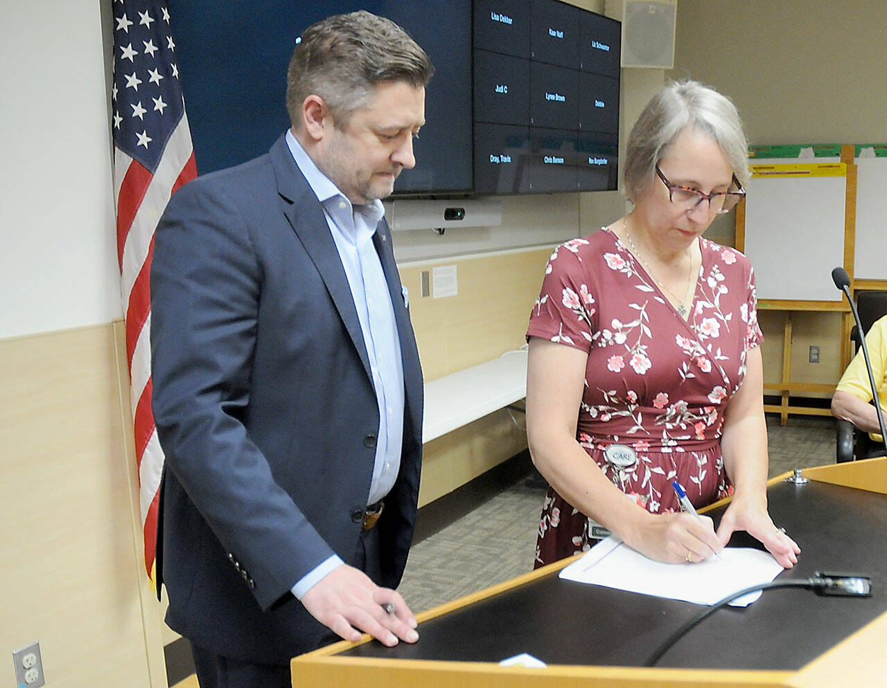 Brad Simmons, president of UW Medicine Hospitals & Clinics, left, looks on as Olympic Medical Center Board President Ann Henninger signs a letter of intent on Wednesday to pursue an operating agreement between the two organizations. (Keith Thorpe/Peninsula Daily News)