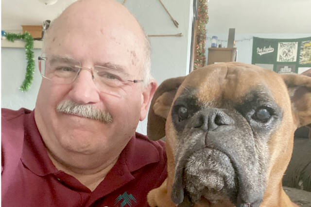Longtime retired Port Angeles High School teacher and public address announcer Pete Rennie is stepping away from the mic to increase his time volunteering with Olympic Medical Center's Therapy Dog program with his three-legged boxer Tripp.