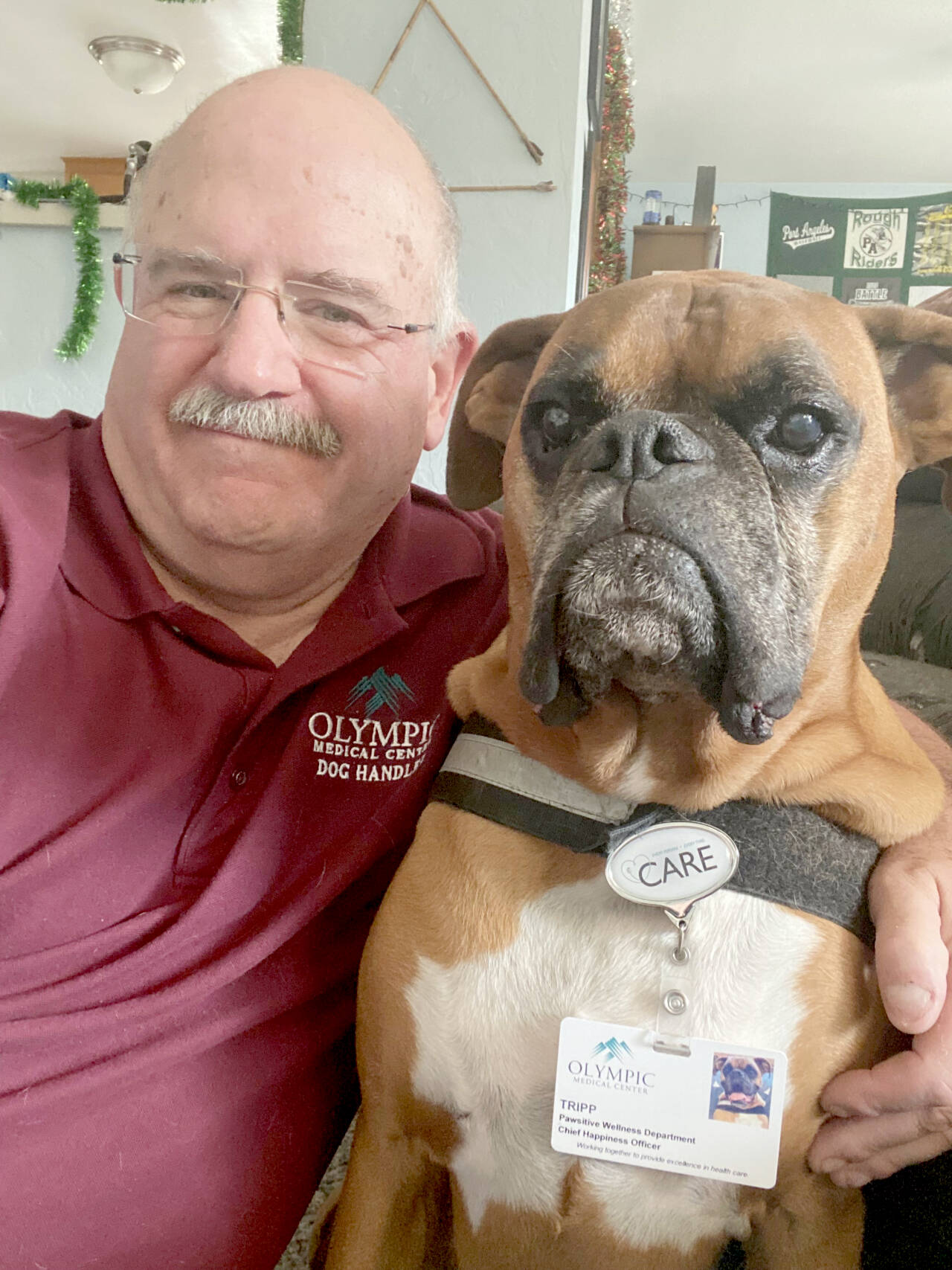 Longtime retired Port Angeles High School teacher and public address announcer Pete Rennie is stepping away from the mic to increase his time volunteering with Olympic Medical Center’s Therapy Dog program with his three-legged boxer Tripp.