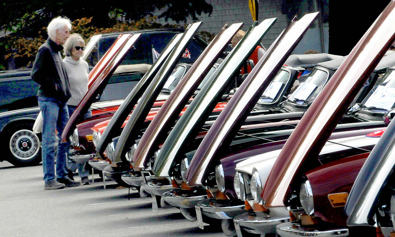 Harvey and Sue Anderson of Minneapolis, Minn., examine a line of classic Triumph automobiles during a Triumph car show on Saturday in the parking lot of the Clallam County Courthouse in Port Angeles. The Tyee Triumph Club hosted the event, which drew about 80 of the cars from around the Pacific Northwest. (Keith Thorpe/Peninsula Daily News)