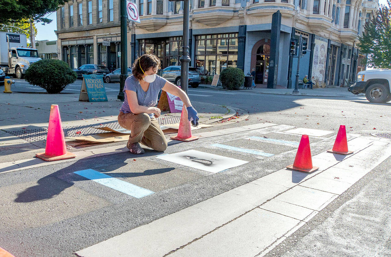 Connie Segal of Port Townsend spray paints a graphic by local artist Timbul Cahyono on the crosswalk at Taylor and Water streets in downtown Port Townsend on Wednesday. The graphics are outside the Port Townsend Film Festival’s temporary lounge on the corner and make for a light-hearted entrance to the festival, which will host its Opening Night gala tonight. Films will be screened from Friday through Sunday at various locations. (Steve Mullensky/for Peninsula Daily News)