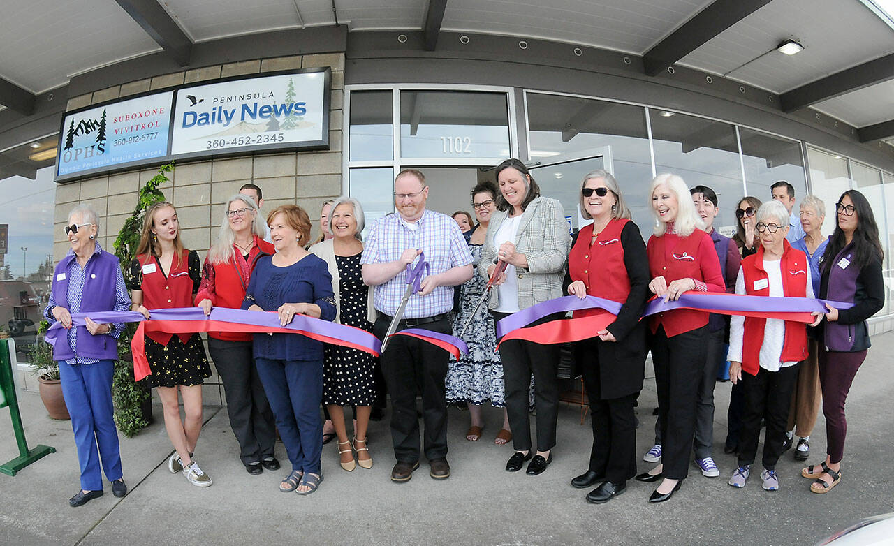 Peninsula Daily News Editor Brian McLean and Publisher Eran Kennedy cut ceremonial ribbons on Thursday in front of the newspaper’s new building at 1102 E. First St. in Port Angeles. Newspaper employees and ambassadors from both the Port Angeles and Sequim-Dungeness chambers of commerce celebrated the event. (Peninsula Daily News)