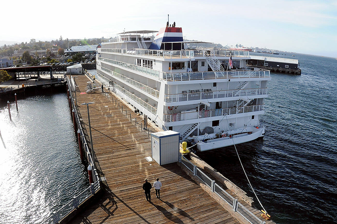 A pair of pedestrians stroll along Port Angeles City Pier past the American Cruise Lines ship American Constitution on Thursday on the Port Angeles waterfront. The ship is one of several used by the company for cruises to ports of call around Puget Sound and the Salish Sea, including Port Angeles and Port Townsend. (Keith Thorpe/Peninsula Daily News)