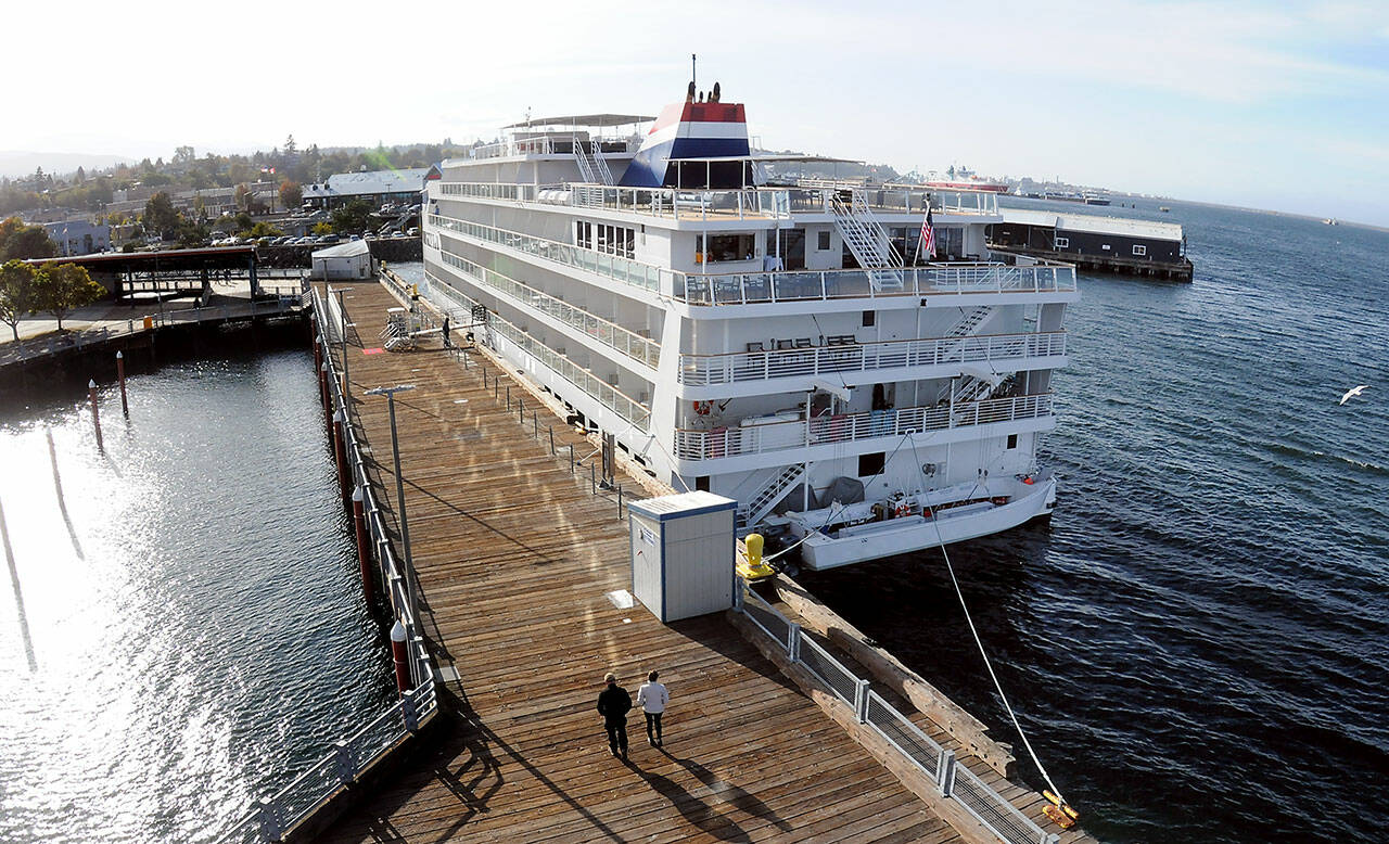 A pair of pedestrians stroll along Port Angeles City Pier past the American Cruise Lines ship American Constitution on Thursday on the Port Angeles waterfront. The ship is one of several used by the company for cruises to ports of call around Puget Sound and the Salish Sea, including Port Angeles and Port Townsend. (Keith Thorpe/Peninsula Daily News)