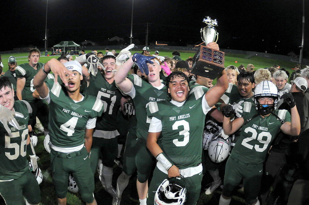 KEITH THORPE/PENINSULA DAILY NEWS Port Angeles’ Asante Korsmo holds up the Rainshadow Rumble trophy as he and the rest of his Roughriders team celebrate Friday night’s 27-14 victory over Sequm at Port Angeles Civic Field.