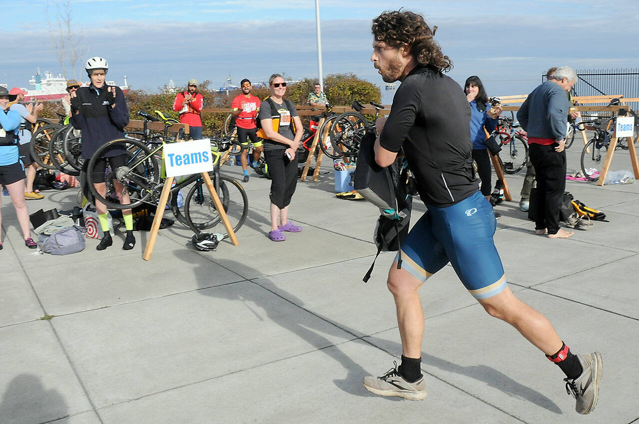 KEITH THORPE/PENINSULA DAILY NEWS Big Hurt iron man competitor Joey Gish of Sequim races through the transfer zone on the way to his kayak after finishing the mountain bike leg of the race in first place on Saturday at Pebble Beach Park in Port Angeles. Gish finished second to Michael Finley, who won the race for the fourth time.