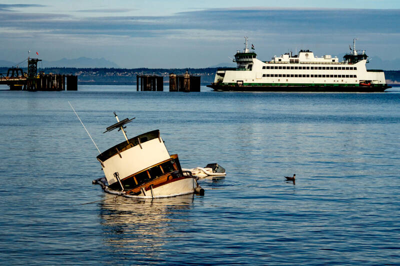 East Jefferson Fire Rescue and the state Department of Ecology responded Sunday to a sunken cabin cruiser that went aground off Indian Point between the ferry dock and Port Townsend Marina. One person on board was treated for injuries. The Washington State Ferry M/V Salish is entering the dock. (Steve Mullensky/for Peninsula Daily News)