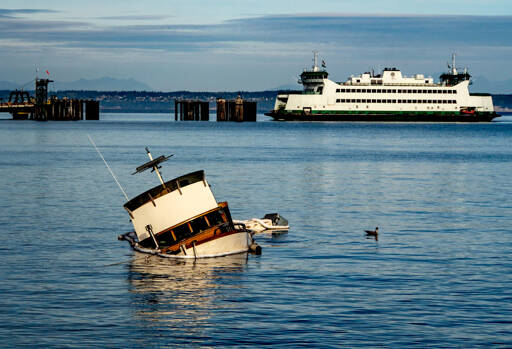 East Jefferson Fire Rescue and the state Department of Ecology responded Sunday to a sunken cabin cruiser that went aground off Indian Point between the ferry dock and Port Townsend Marina. One person on board was treated for injuries. The Washington State Ferry M/V Salish is entering the dock. (Steve Mullensky/for Peninsula Daily News)