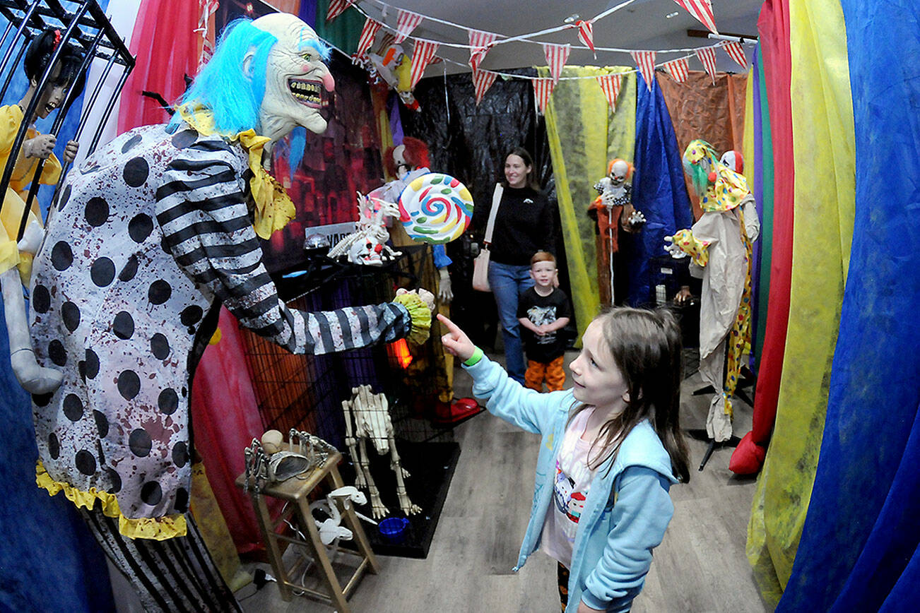Hadley Harp, 7, accompanied by brother Van Harp, 3, and mother Ashton Harp, all of Port Angeles, stroll through a room filled with evil clowns as part of a haunted house set up by the Olympic Peninsula Humane Society in its Kitty City animal shelter west of Sequim. Saturday’s haunted attraction was a highlight of the organization’s Howl-O-‘Ween event that benefitted the humane society along with a food drive for the Sequim Food Bank. (Keith Thorpe/Peninsula Daily News)