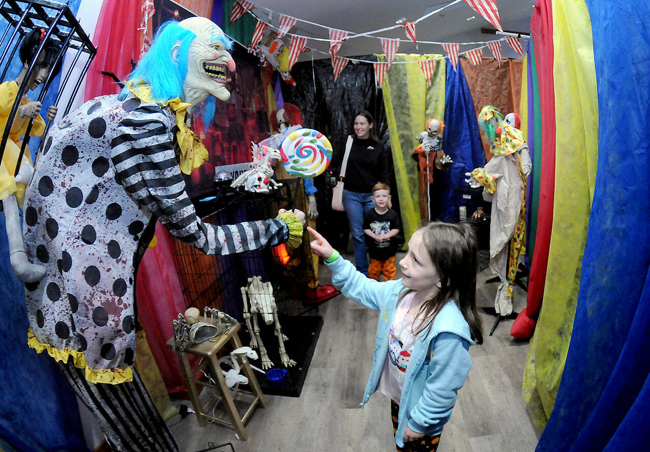 Hadley Harp, 7, accompanied by brother Van Harp, 3, and mother Ashton Harp, all of Port Angeles, stroll through a room filled with evil clowns as part of a haunted house set up by the Olympic Peninsula Humane Society in its Kitty City animal shelter west of Sequim. Saturday’s haunted attraction was a highlight of the organization’s Howl-O-‘Ween event that benefitted the humane society along with a food drive for the Sequim Food Bank. (Keith Thorpe/Peninsula Daily News)