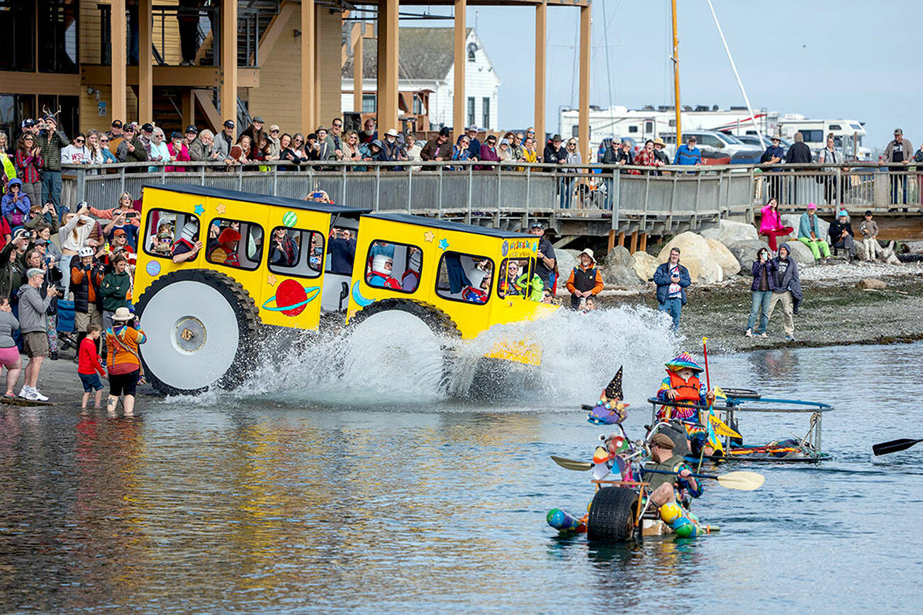 Racers make a big splash as they hit the water after rolling down the boat ramp at Northwest Maritime on Saturday. The 14 entrants in the Kinetic Skulpture race had to prove their floatability by paddling across the bay to the Port Townsend city dock, about a quarter-mile, and back to the ramp before they could participate in Sunday’s event. (Steve Mullensky/for Peninsula Daily News)