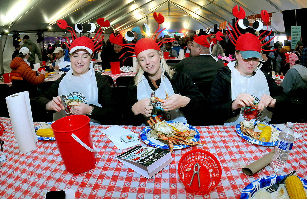 Festival-goers, from left, Cara Saunto, Shelby Damiani and Adrienne Bohannon, all of Seattle, crack into their crab dinners on Saturday at the Dungeness Crab Festival on the Port Angeles waterfront. The annual event drew thousands of visitors to downtown Port Angeles for a variety of seafood delights, music, cooking demonstrations, a craft fair and other activities. (Keith Thorpe/Peninsula Daily News)