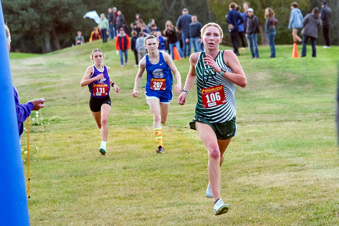 Emily Matthiessen/for Peninsula Daily News
Port Angeles senior Leia Larson, front, eyes the finish line while Sequim freshman Emily Bair (back) overtakes Olympic's Abigail Thatcher to earn a top-5 finish at the Olympic League Cross Country Championships at The Cedars at Dungeness Golf Course on Thursday.