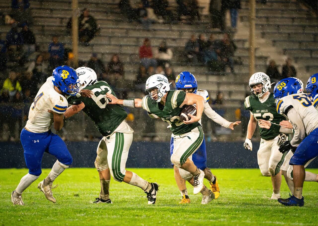 Port Angeles running back Dylan Mann (22) gets blocking from teammate Stryder Wilhelm (62) as he rushes for some of his 101 yards Friday night against Bremerton. The Knights won in extremely wet conditions 21-0. (Diamond Gentile/for Peninsula Daily News)
