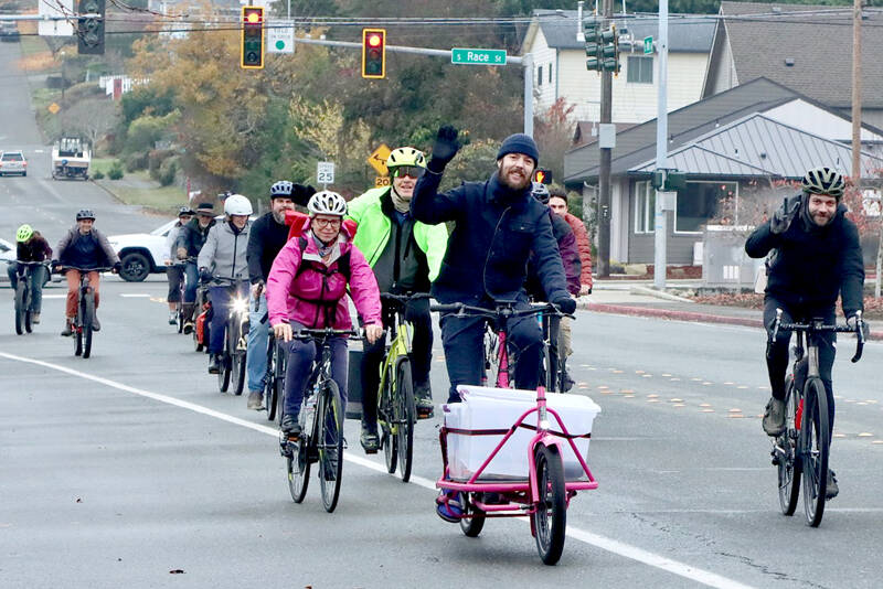 Matthew Moore, center, leads a group of Cranksgiving bicyclists on Eighth Street in Port Angeles using his specially build “cargo bike” to collect and transport purchased goods. The annual Cranksgiving food drive was held Saturday as 14 bike riders visited four different grocery stores and used their own money to buy food for the Port Angeles Food Bank. A total of 254 pounds was collected. A similar Cranksgiving event is scheduled for Sequim on Saturday. (Dave Logan/for Peninsula Daily News)