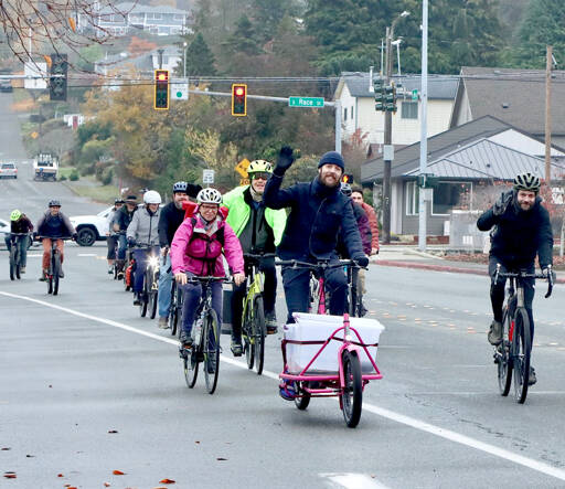 Matthew Moore, center, leads a group of Cranksgiving bicyclists on Eighth Street in Port Angeles using his specially build “cargo bike” to collect and transport purchased goods. The annual Cranksgiving food drive was held Saturday as 14 bike riders visited four different grocery stores and used their own money to buy food for the Port Angeles Food Bank. A total of 254 pounds was collected. A similar Cranksgiving event is scheduled for Sequim on Saturday. (Dave Logan/for Peninsula Daily News)