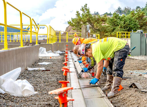 Workers from Van Ness Construction of Port Hadlock smooth out newly poured curbs and gutters on Tuesday as part of the Port of Port Townsend’s stormwater recovery system, an ongoing project at the Port Townsend Marina. (Steve Mullensky/for Peninsula Daily News)