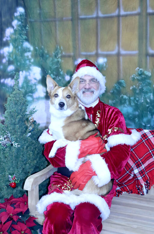 Christopher Thomsen, portraying Santa Claus, holds a corgi mix named Lizzie on Saturday at the Airport Garden Center in Port Angeles. All proceeds from the event were donated to the Peninsula Friends of Animals. (Dave Logan/for Peninsula Daily News)