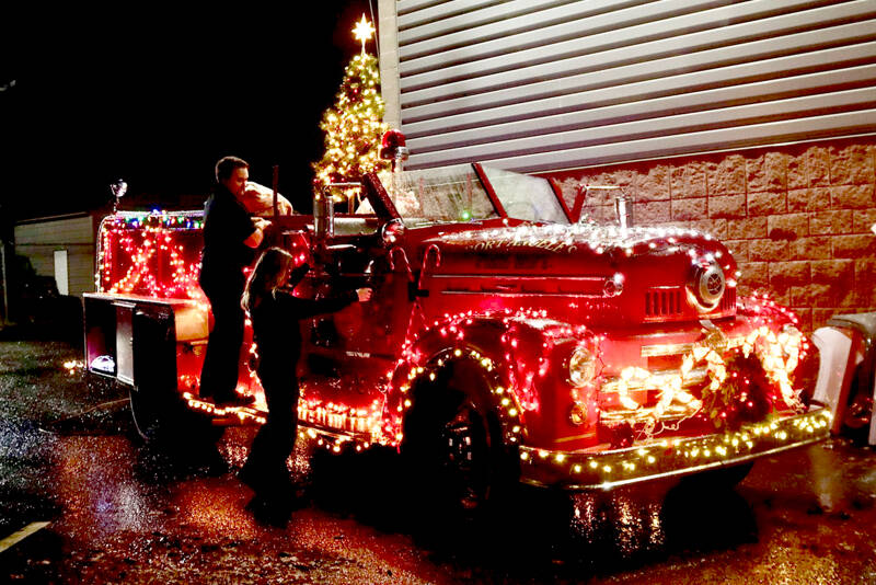 Firefighters Tyler Gage and Tatiana Hyldahl check out the light connections on the 1956 fire truck that will travel the streets of Port Angeles during the 41st Operation Candy Cane beginning Monday. Santa and his helpers will pass out candy canes to those who donate food items or cash. The runs will begin at 5:30 p.m. and include the following areas: Monday, west of I street and M street; Tuesday, I and L streets to C street; Wednesday, C Street to Lincoln Street; Thursday, Chase Street to Chambers Street; Friday, Jones Street to Golf Course Road; Dec. 13, above Lauridsen Boulevard. It will be stationary from 5:30 p.m. to 7 p.m. on Dec. 14 at the Port Angeles Grocery Outlet and during the same time on Dec. 15 at Lower Elwha Food and Fuel. (Dave Logan/for Peninsula Daily News)