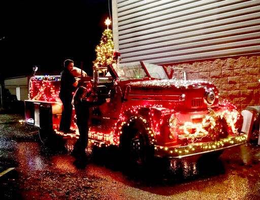 Firefighters Tyler Gage and Tatiana Hyldahl check out the light connections on the 1956 fire truck that will travel the streets of Port Angeles during the 41st Operation Candy Cane beginning Monday. Santa and his helpers will pass out candy canes to those who donate food items or cash. The runs will begin at 5:30 p.m. and include the following areas: Monday, west of I street and M street; Tuesday, I and L streets to C street; Wednesday, C Street to Lincoln Street; Thursday, Chase Street to Chambers Street; Friday, Jones Street to Golf Course Road; Dec. 13, above Lauridsen Boulevard. It will be stationary from 5:30 p.m. to 7 p.m. on Dec. 14 at the Port Angeles Grocery Outlet and during the same time on Dec. 15 at Lower Elwha Food and Fuel. (Dave Logan/for Peninsula Daily News)