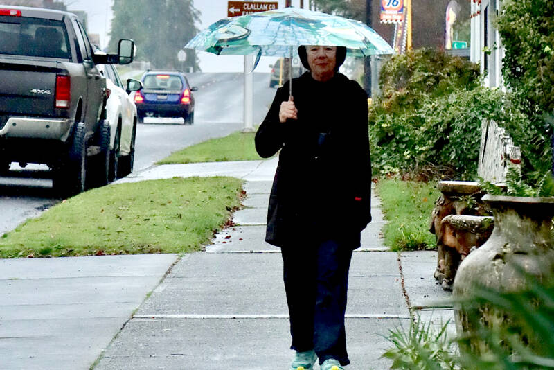 Sue Bahl walks with an umbrella on West Eighth Street on Monday. Heavy rainfall up to 8 inches over the past several days has increased the threat of landslides in Western Washington, according to the National Weather Service. A flood watch also has been issued until 4 p.m. Friday for portions of northwest and west central Washington, including Clallam and Jefferson counties. Sharp rises in rivers, especially those flowing off the Olympics and Cascades, are expected, the National Weather Service said. (Dave Logan/for Peninsula Daily News)