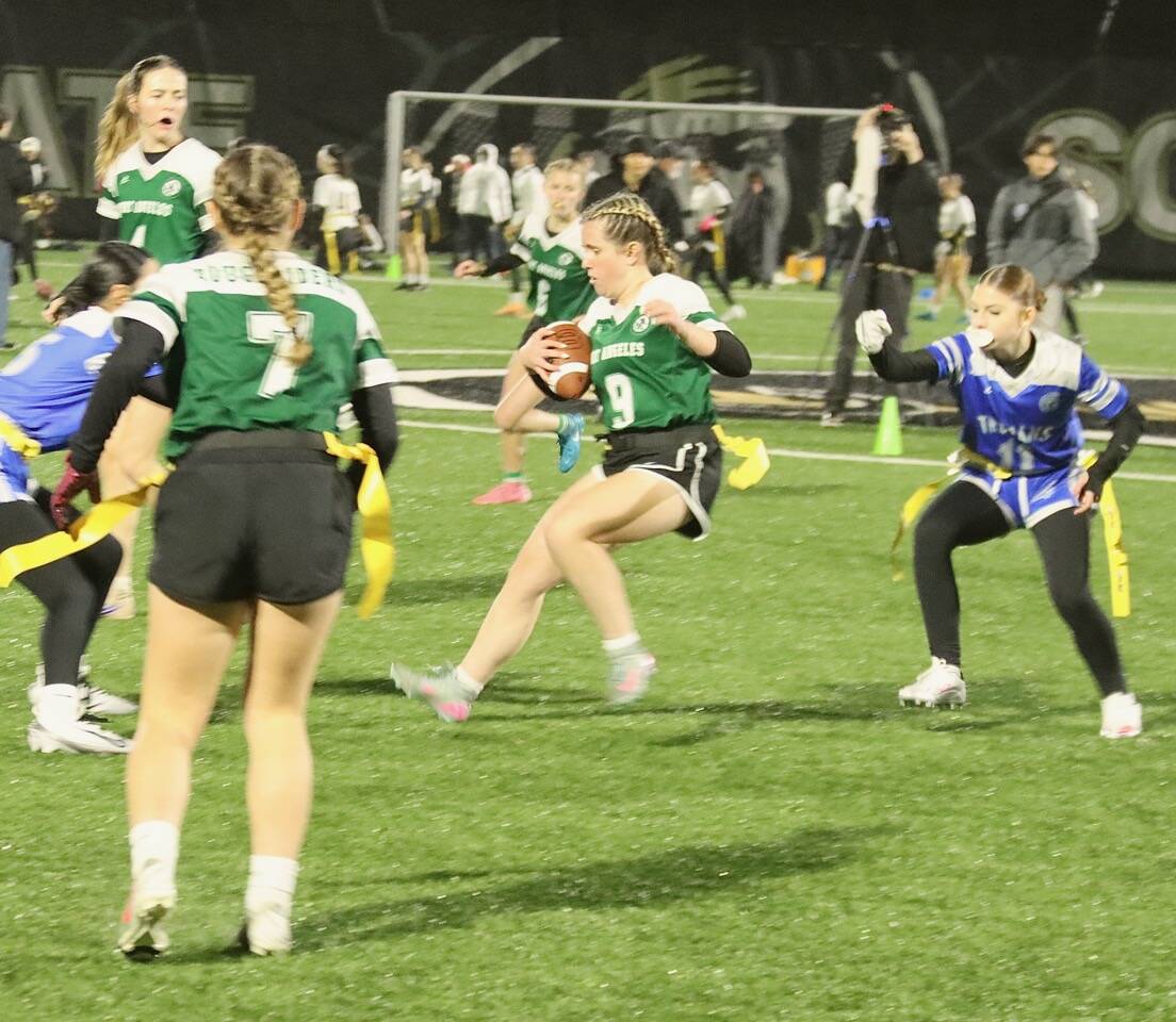 Dave Logan/for Peninsula Daily News 
Port Angeles’ Allison Fricker avoids Olympic Trojan Kathryn James, right, trying to strip her flag during their flag football match Thursday evening in a heavy mist at Wally Sigmar Field at Peninsula College. The Roughriders beat Olympic 42-0 and Kingston 42-35 to improve to 3-1. Sequim (3-1) edged North Kitsap 15-14 and lost to Klahowya 35-6.