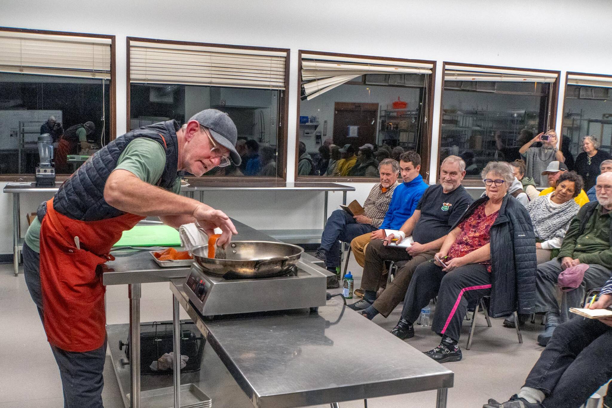 Chef Arron Stark gently inserts a piece of king salmon into a hot saute pan so as not to cause a splatter of hot oil. Stark was presenting a cooking demonstration on Wednesday at the Jefferson County Fairgrounds to 35 people who paid $30 each to learn from an expert. (Steve Mullensky/for Peninsula Daily News)