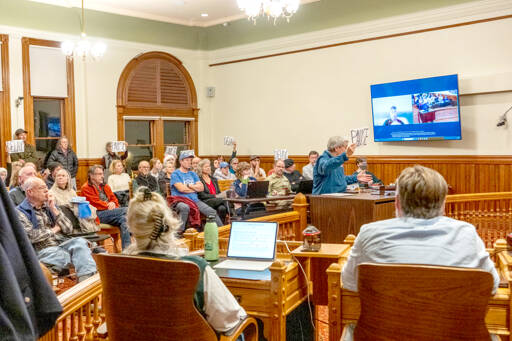 Judy Krebs of Port Townsend speaks to the Port Townsend City Council on Monday to voice her concerns regarding the council’s pending vote on the 2026 Comprehensive Plan and development regulations. Krebs holds a sign that reads “pause,” as do others, entreating the council to delay its vote on passing the plan. About 65 citizens filled the chamber to capacity for the meeting. (Steve Mullensky/for Peninsula Daily News)