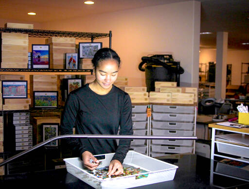 Art Director Aviela Maynard quality checks a mushroom glow puzzle. (Beckett Pintair)