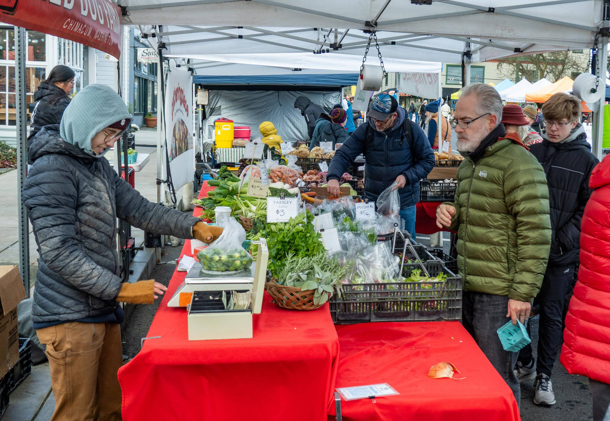 Joe McDonald, from Fort Worth, Texas, purchases a bag of Brussels sprouts from Red Dog Farm on Saturday, the last day of the Port Townsend Farmers Market in Uptown Port Townsend. The market will resume operations on the first Saturday in April 2026. (Steve Mullensky/for Peninsula Daily News)