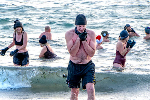 Tom Malone of Port Townsend, seeks the warmth of a towel and a shirt as he leaves the 46-degree waters of the Salish Sea on Saturday after he took a cold plunge to celebrate the winter solstice. “You can’t feel the same after doing this as you did before,” Malone said. (Steve Mullensky/for Peninsula Daily News)