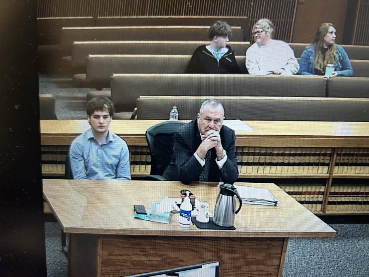 Cole Douglas, who was sentenced Thursday after he pleaded guilty to the March 2025 hit and run that seriously injured Sequim middle-schooler Colton Dufour, listens to Judge Elizabeth Stanley as Colton’s mother, Cherie Tachell, seated several rows back, smiles at her son just minutes before Douglas was taken into custody to begin serving a 12-month jail sentence. Seated beside them is victims advocate Molly Ramsey, who works in the Clallam County prosecuting attorney’s office and read a victim’s impact statement to the court during hearing. (Clallam County Superior Court)