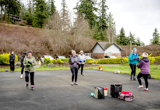 TJ Plastow, right, in purple coat, leads Let’s Keep Moving, an outdoor fitness class at Port Ludlow Marina on Friday. The class participants are known to show up in all weather. On Friday, it was 40 degrees and breezy. (Steve Mullensky/for Peninsula Daily News)