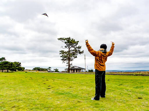 Wedner Klebanow uses both arms to control a kite at Fort Worden State Park on Sunday. She was with her father, Rick Klebanow, in 16 mph winds, strong enough for the kite to perform certain stunts. (Steve Mullensky/for Peninsula Daily News)