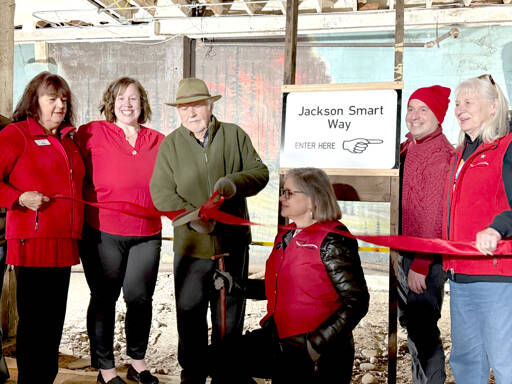 Jackson Smart, center with scissors, cuts the ribbon on Wednesday to officially open the newly remodeled section of the Port Angeles Underground Tour. With Smart are, from left, Julie Hatch, Kara Anderson, Elisa Simonsen, Sam Grello and Johnetta Bindas. (Laurel Hargis)